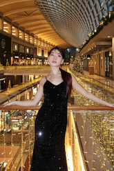 a lady in a black velvet spaghetti strap dress with sequins